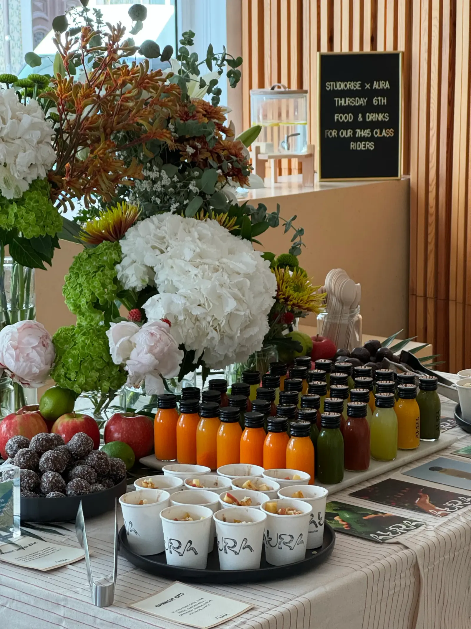 Aura event table with cold-pressed juices in glass bottles, energy balls and flowers
